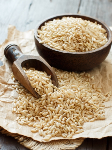 Brown rice in a bowl with a wooden spoon